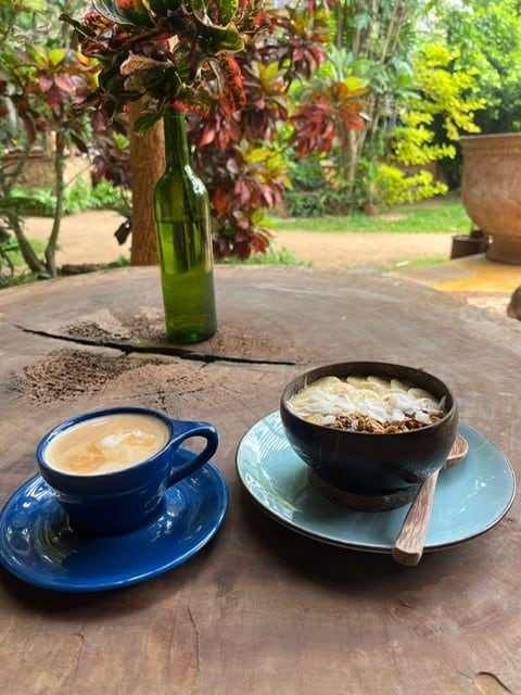 A cup of coffee and breakfast bowl on a wooden table