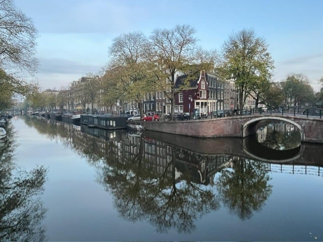 view of a canal crossed by a bridge with trees and houses 