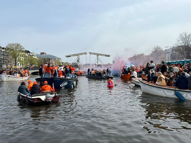 people wearing orange clothing on boats on a canal