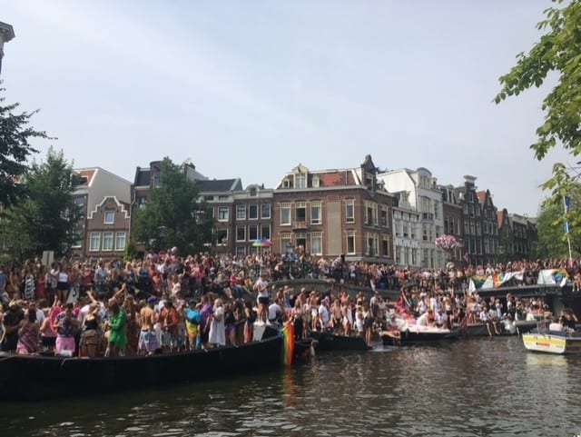 people standing on boats on a canal with buildings in the background