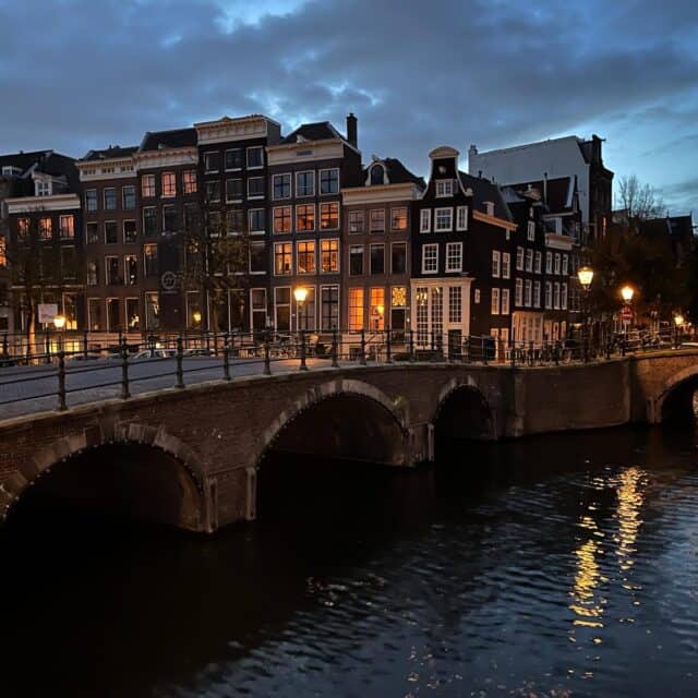 street view of a bridge over a canal with buildings on the background