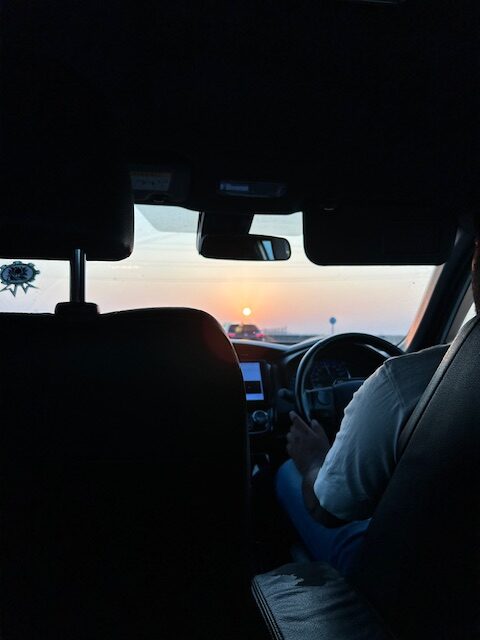 man drives a car at sunrise
