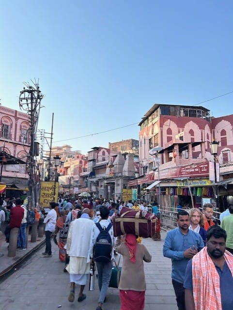 people walking in a street surrounded by pink buildings