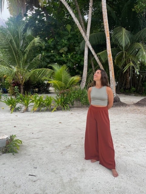woman in red pants standing in front of palm trees thinking which is the beste esim