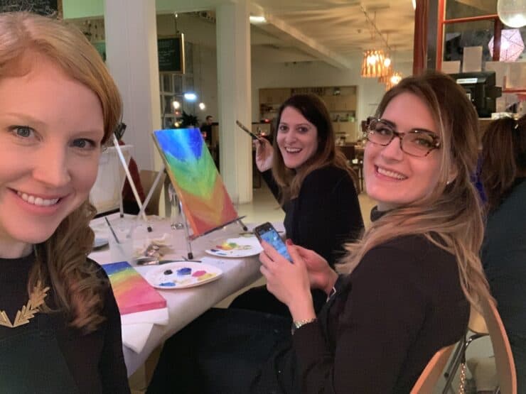 3 women smiling while painting 