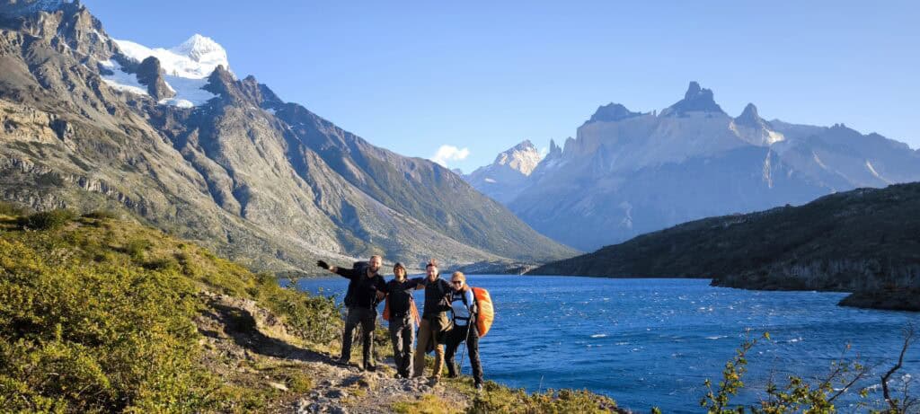 4 people smiling in front of a lake with mountains surrounding them