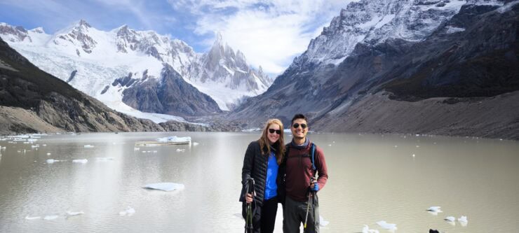 A man and women smiling standing next to lake Torre