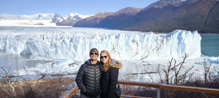 Man and Woman standing in front of a large blue glacier in Patagonia Argentina
