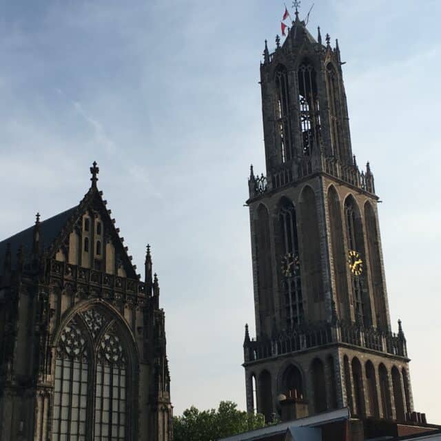 The Gothic Dom Tower and cathedral in Utrecht standing separately against a pale sky