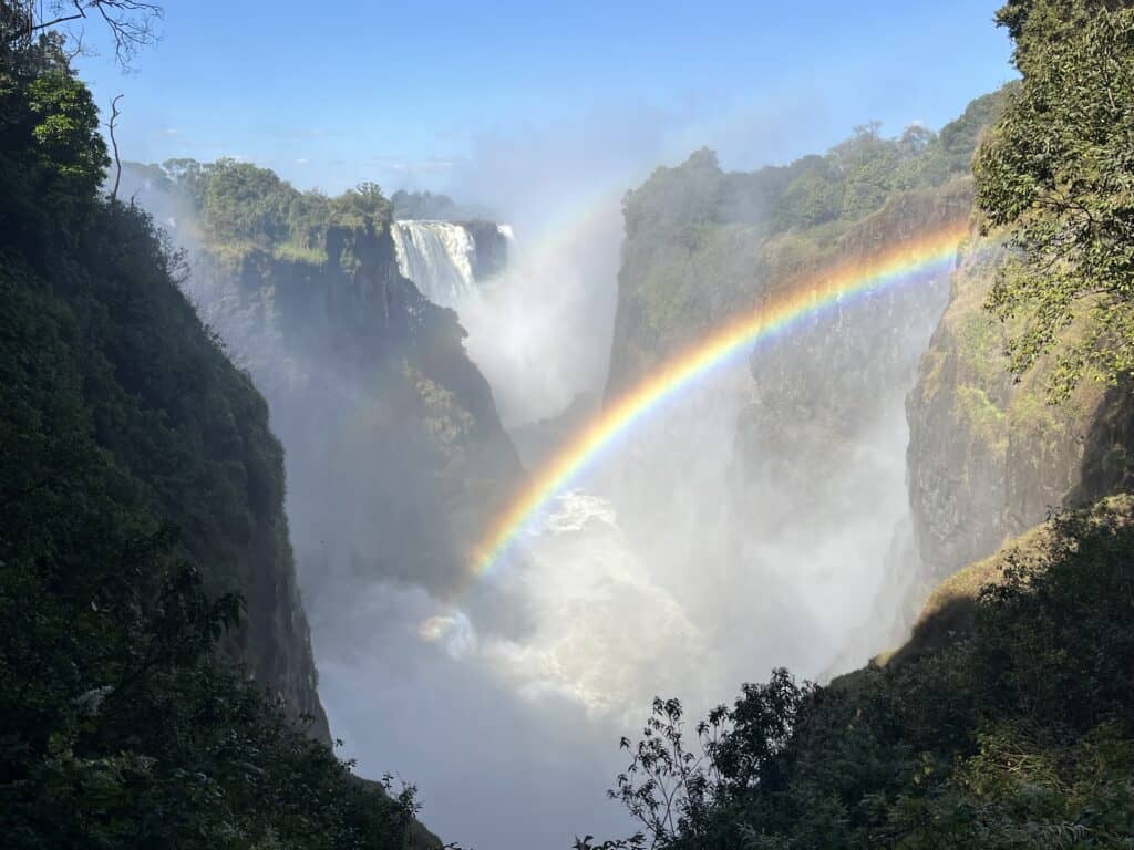 Double rainbow arching over the spray of Victoria Falls, seen from the Zimbabwe side
